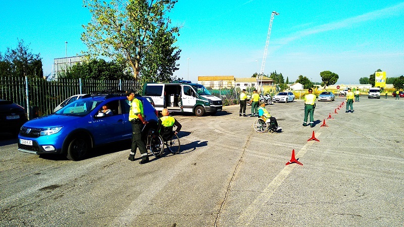 Fotografía de la campaña. Voluntarios en silla de ruedas informando a conductores de vehículos.