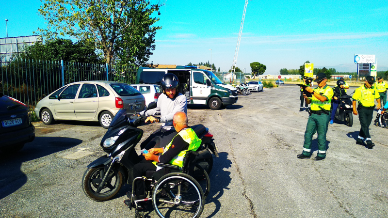 Fotografía de la campaña. Voluntario en silla de ruedas informando a un motorista