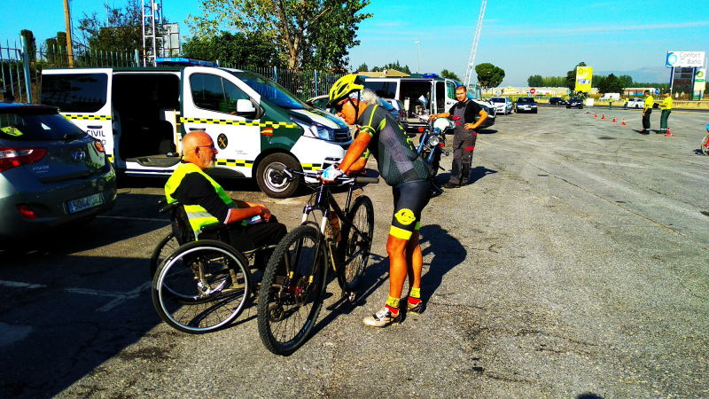 Fotografía de la campaña. Voluntario en silla de ruedas informando a un cliclista